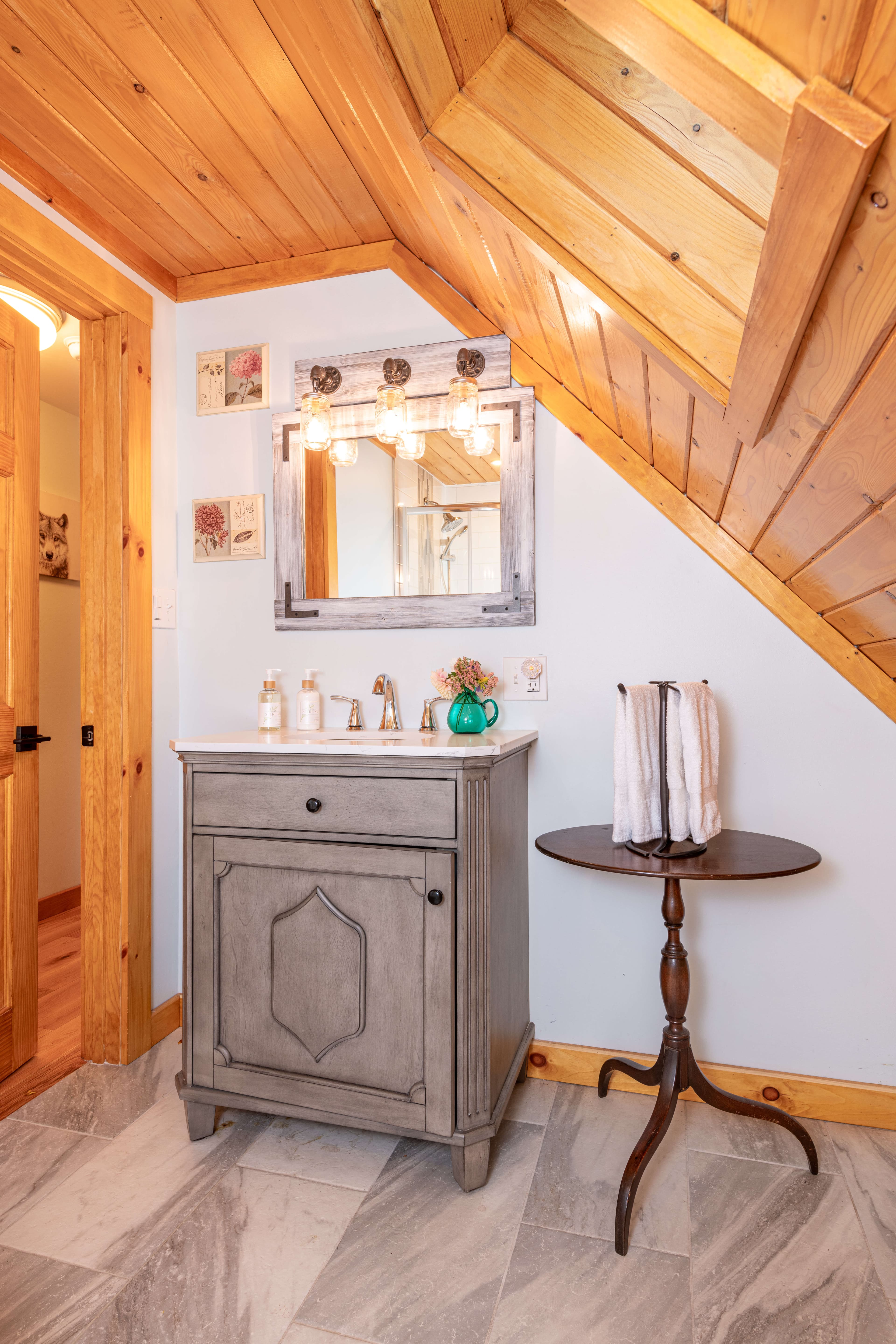 Gray wooden vanity with lighted mirror, occasional table with hand towels