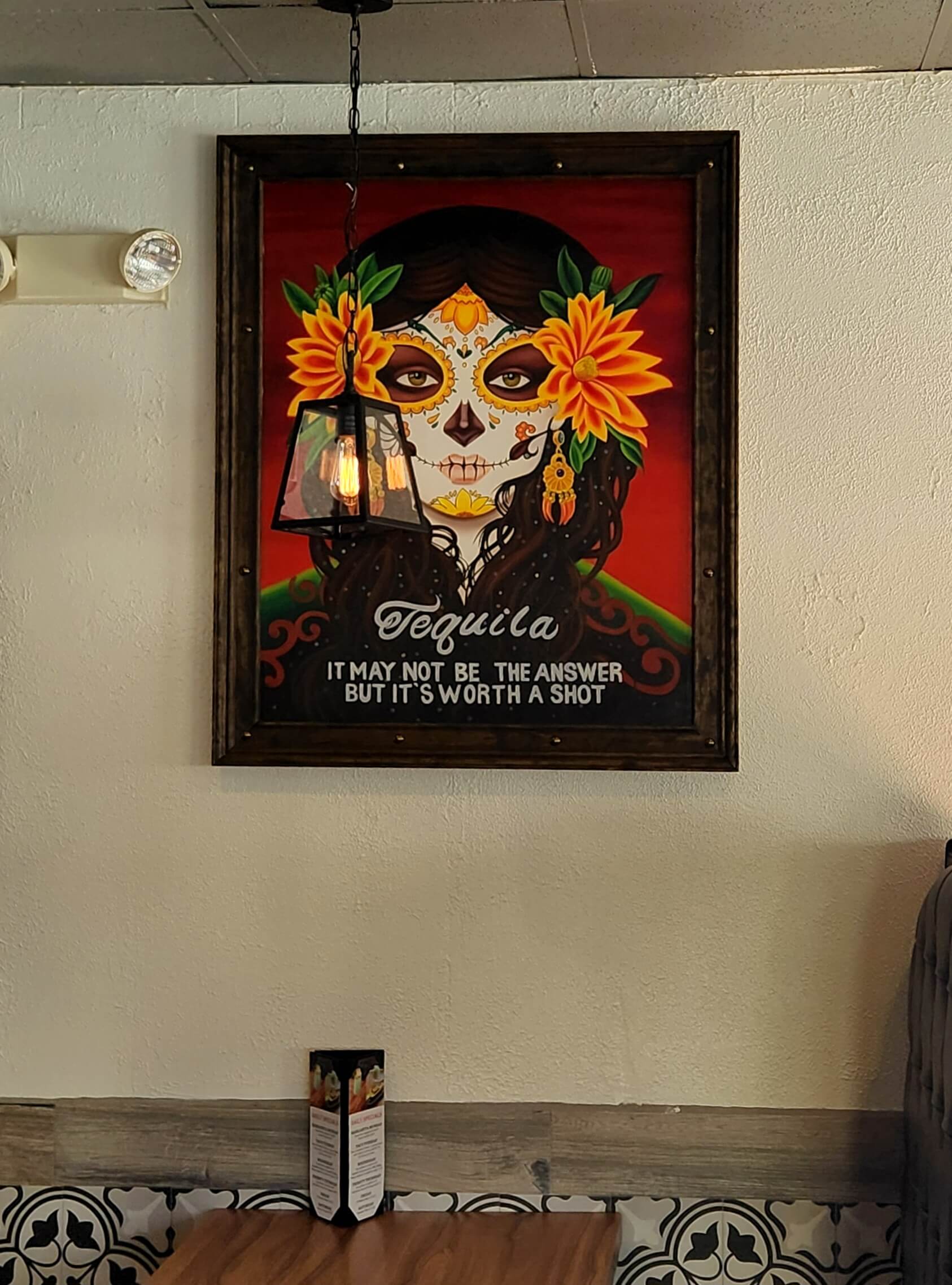 A vibrant mural of a decorated skull with flowers, featuring the quote "Tequila: It may not be the answer, but it's worth a shot."