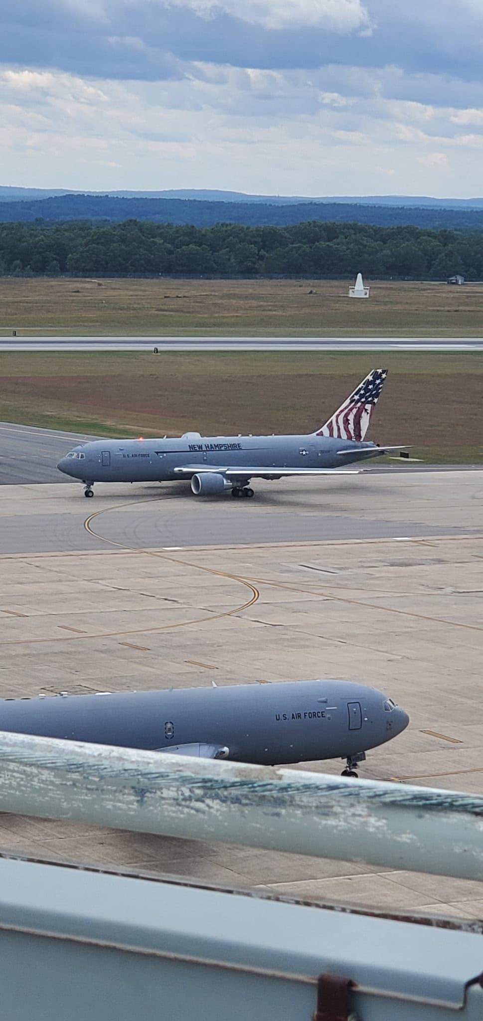 Two military aircraft are on a runway, with one displaying an American flag design on its tail.