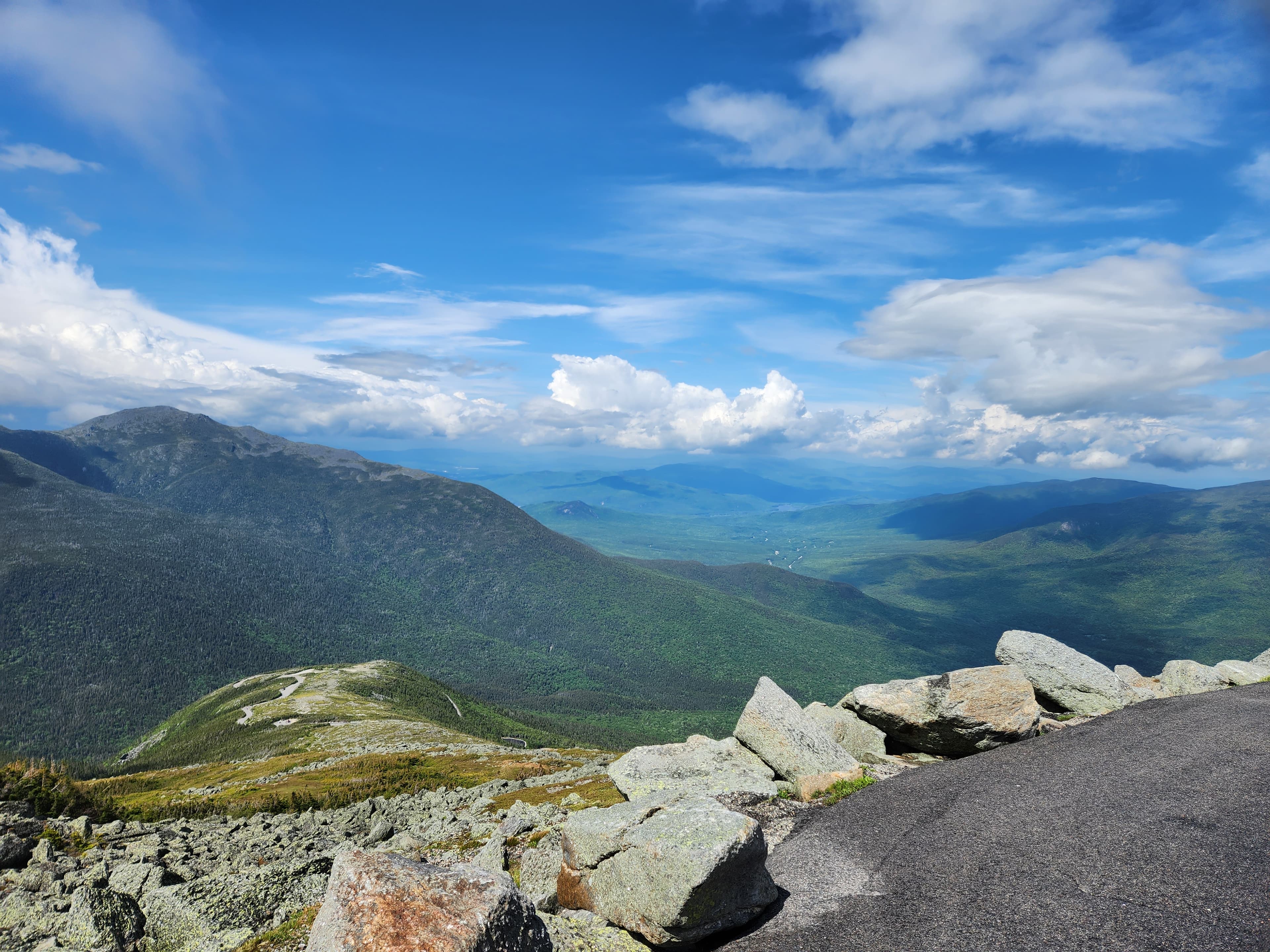 A panoramic view of lush green mountains and a blue sky filled with clouds.