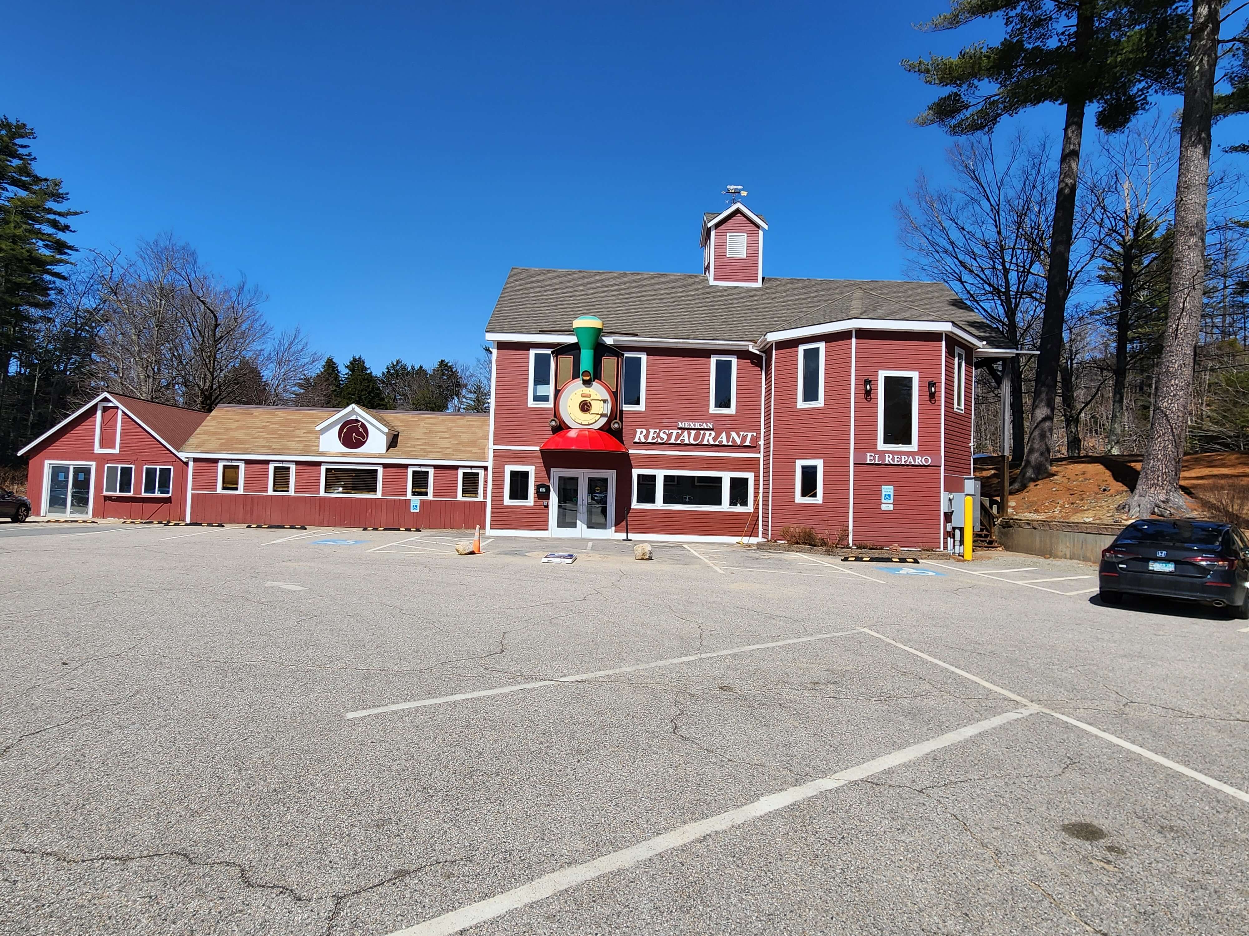A red, barn-style restaurant building with a clock tower and a train-themed sign.