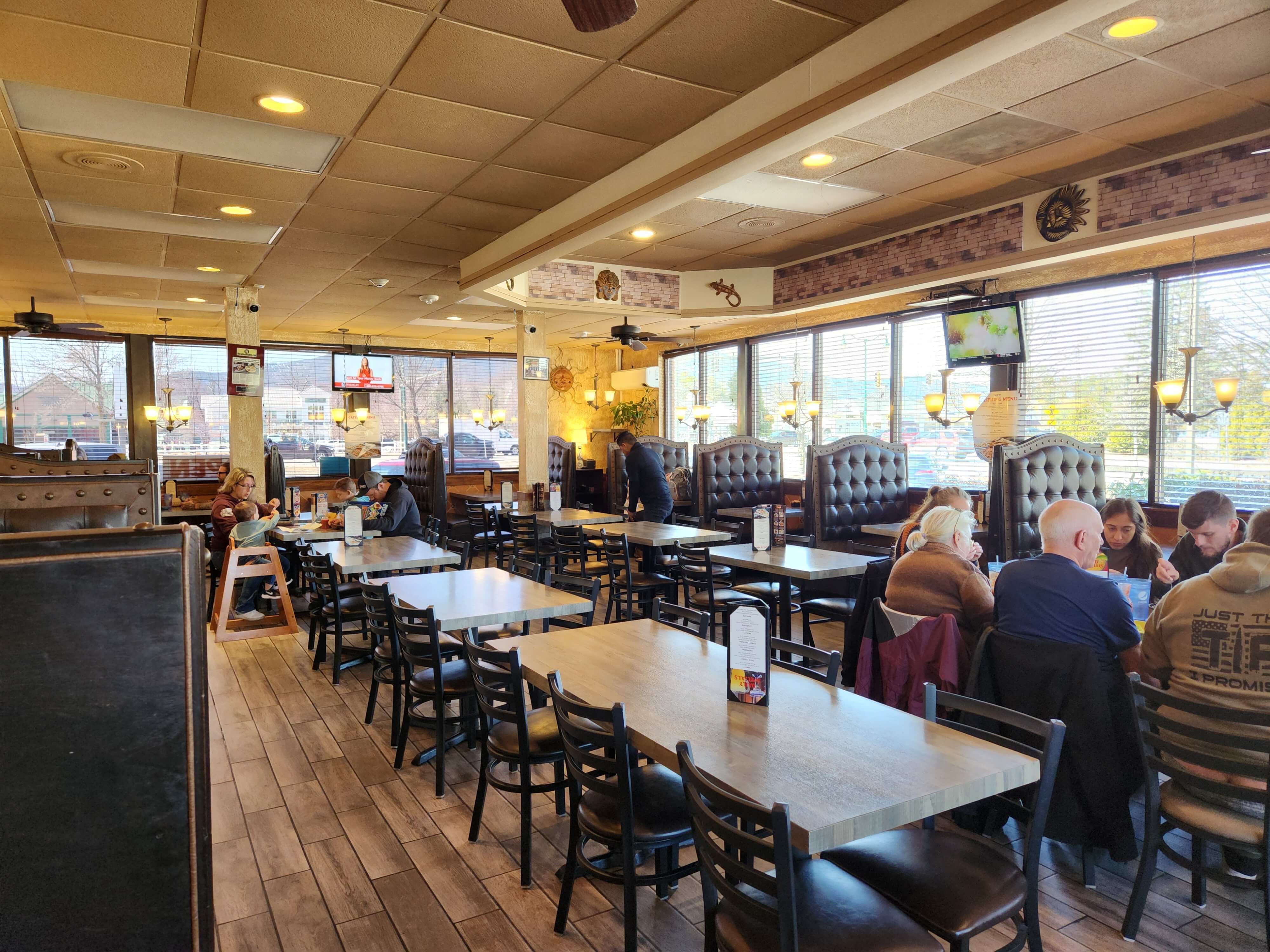 A bright, spacious restaurant with empty tables and several groups of customers dining.
