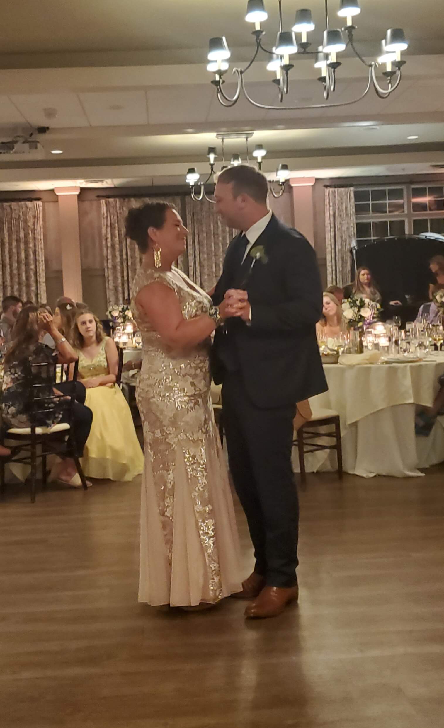 A couple dances during a wedding reception in a warmly lit venue.