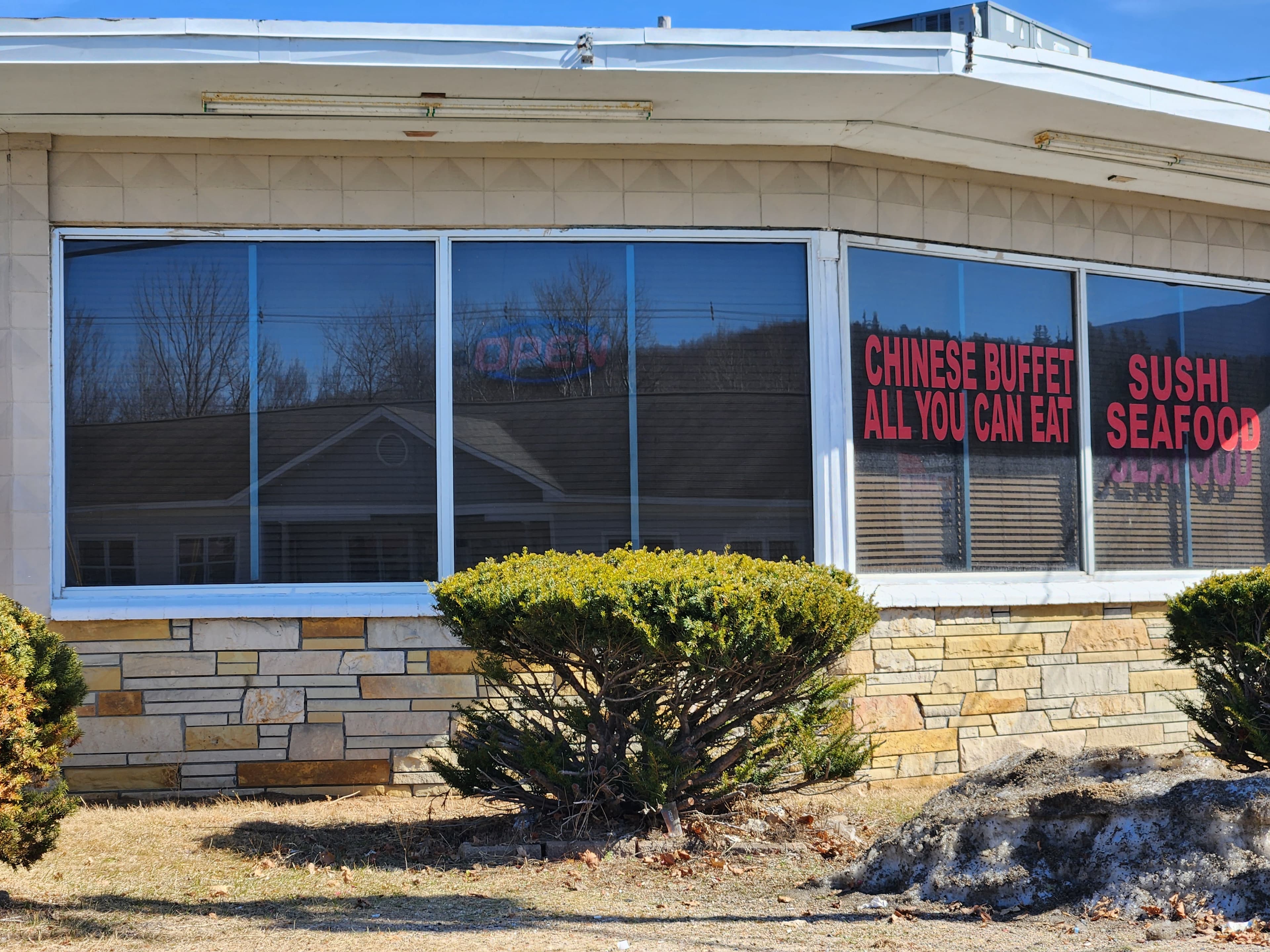 Window of a restaurant featuring signs for a Chinese buffet and sushi seafood.