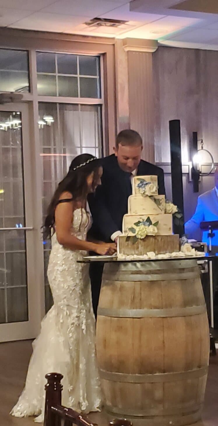 A bride and groom cut their wedding cake together at a celebration.