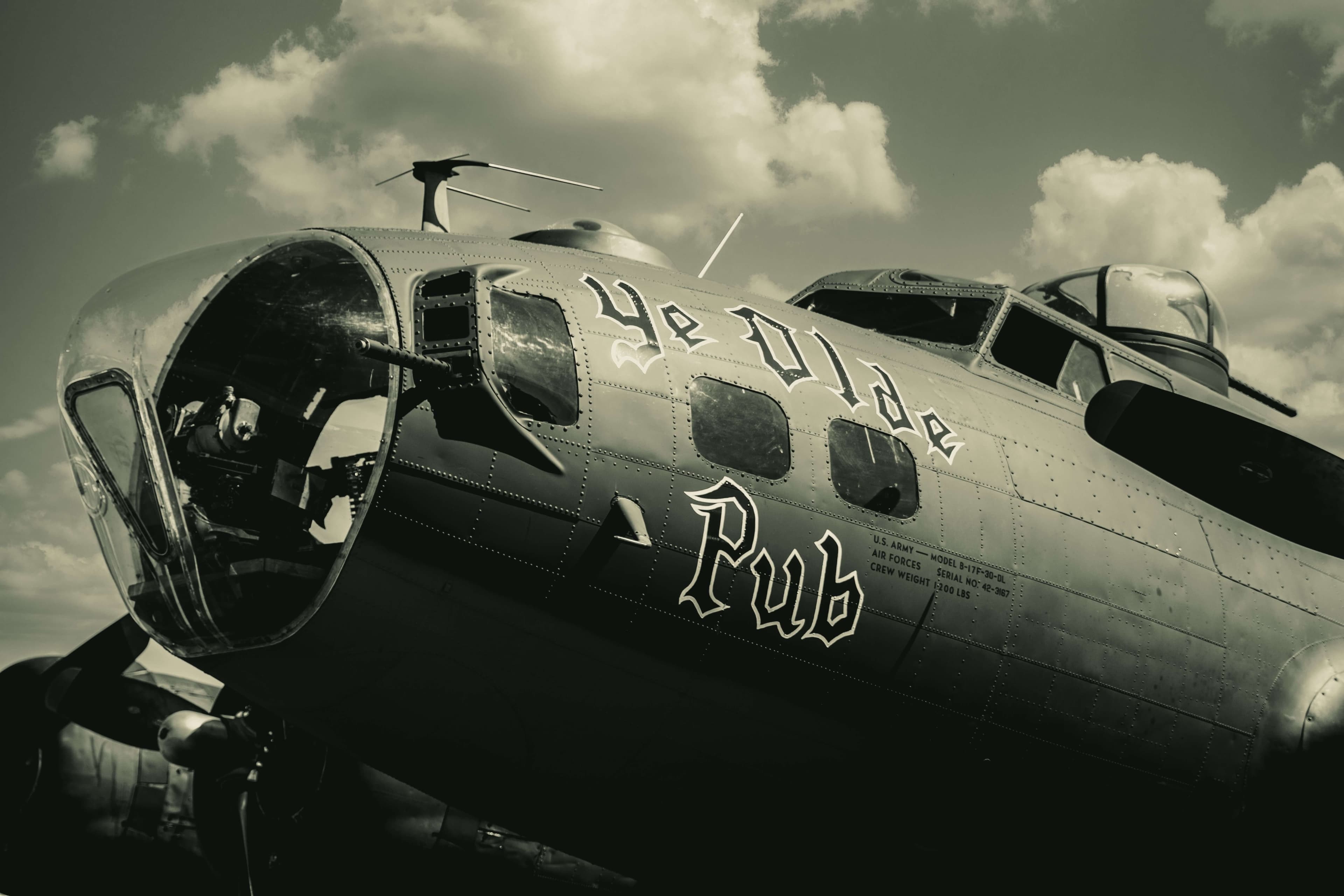 A vintage aircraft with "Ye Olde Pub" painted on its fuselage against a cloudy sky.