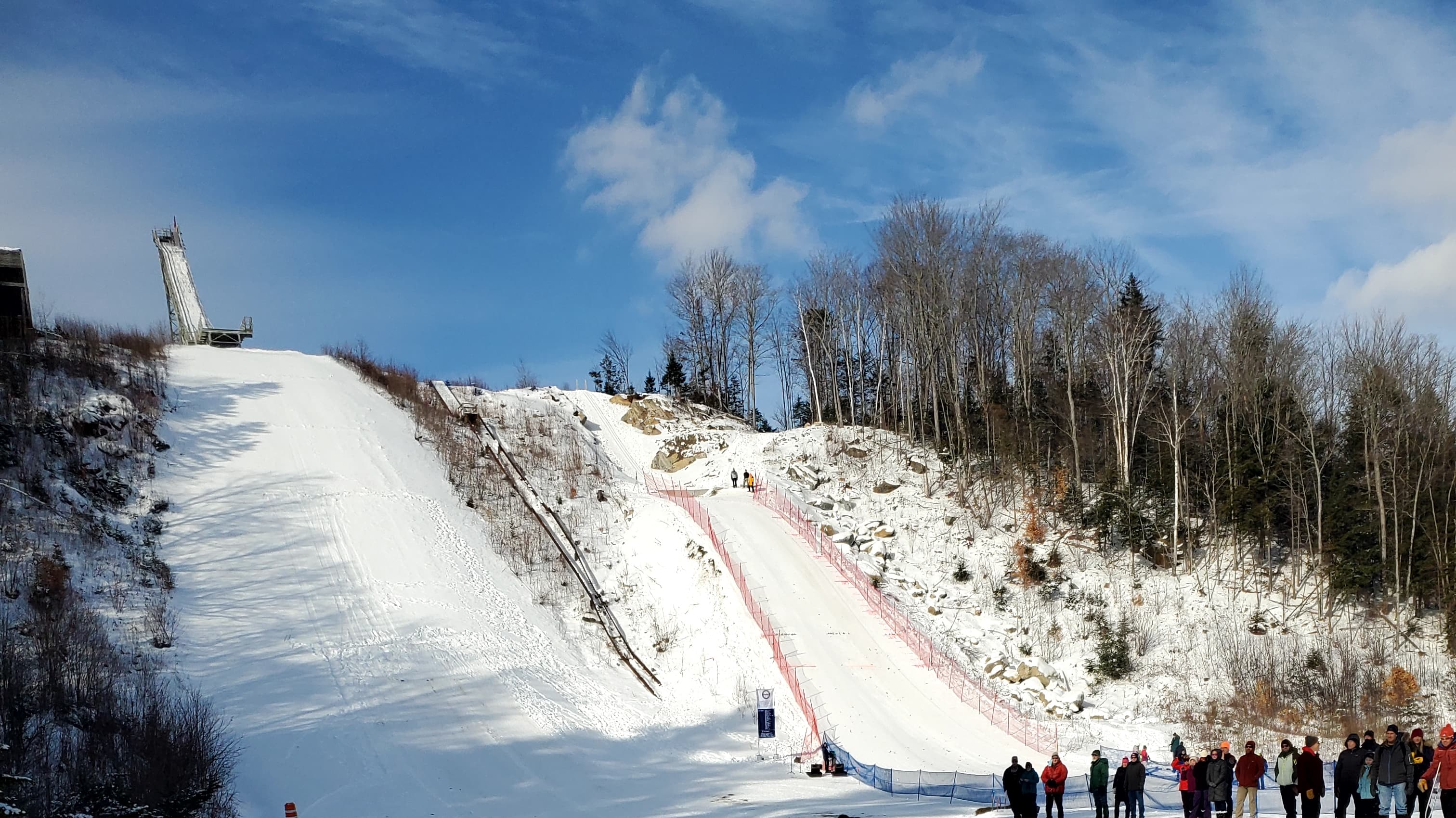 Ski slopes with a jump ramp and spectators in a snowy landscape. Ski slopes with a jump ramp and spectators in a snowy landscape.