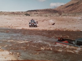 A man trying to attach a winch to a truck sunken in a river