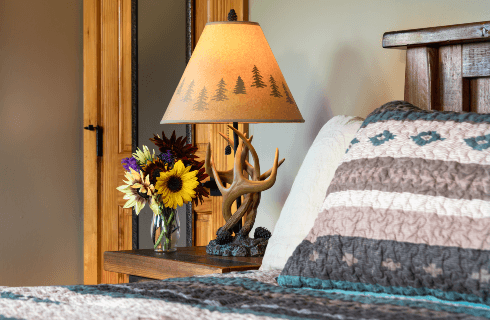 Sunflowers and antler lamp next to a bed