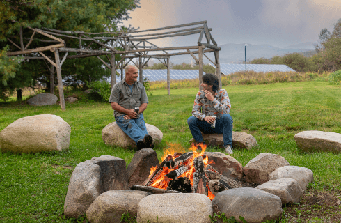 Two men in front of a blazing firepit
