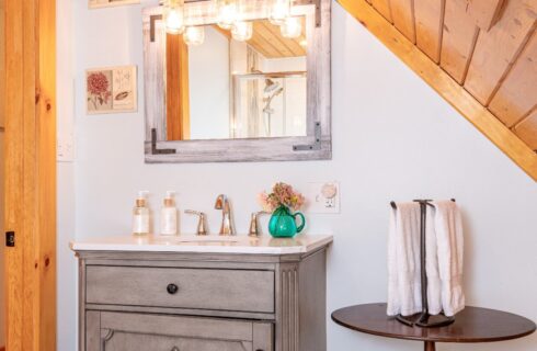 Gray vanity and mirror with white sink and small towel table