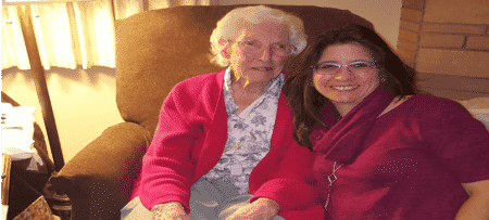 An elderly woman next to a dark haired woman