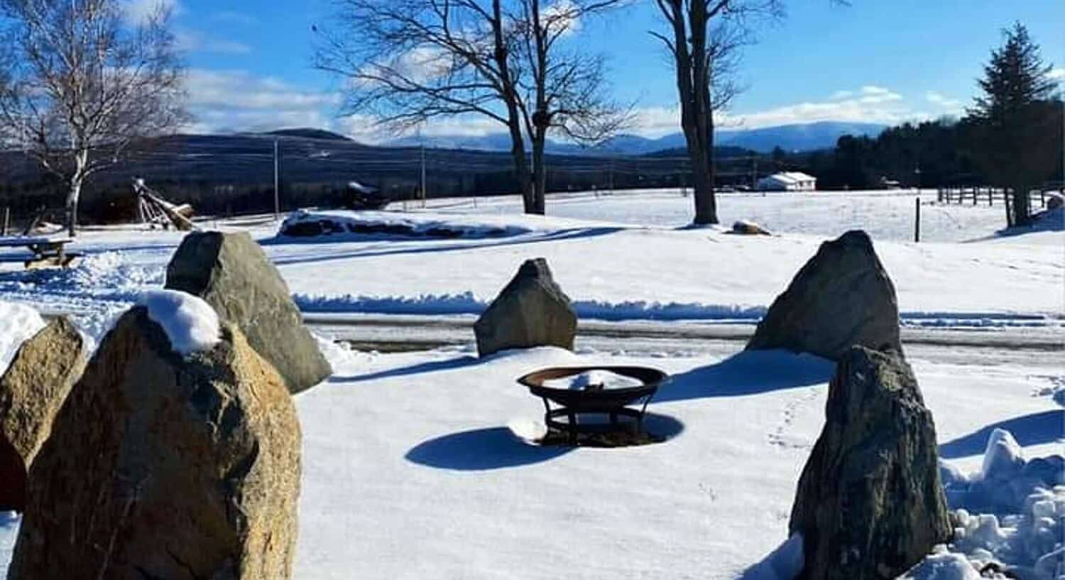 Fire pit surrounded by six tall pointed rocks during winter
