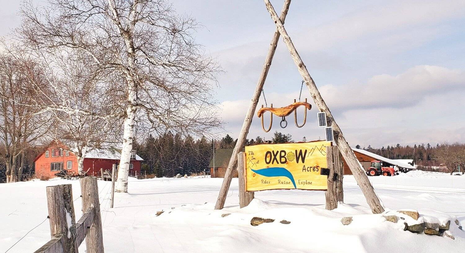 Large wooden sign that says The Inn at Oxbow Acres with oxen yoke on top